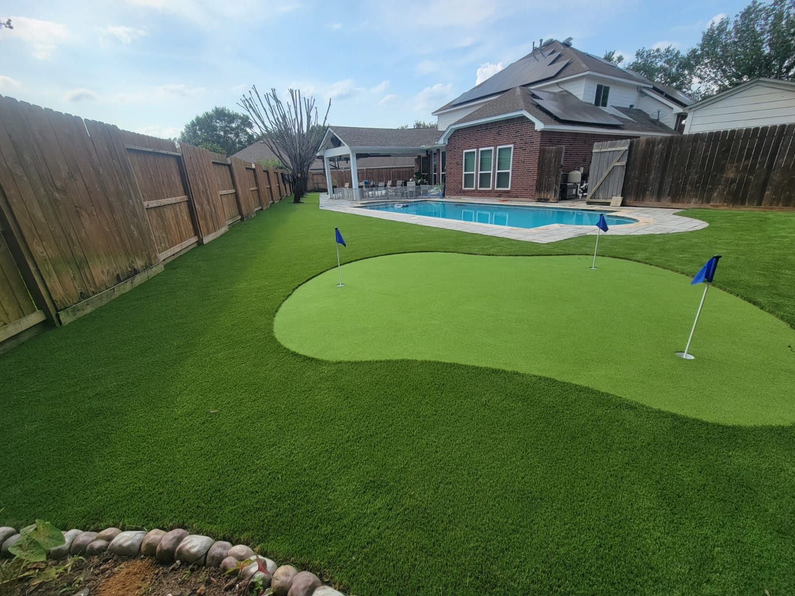 Backyard putting green and turf wrapping a pool